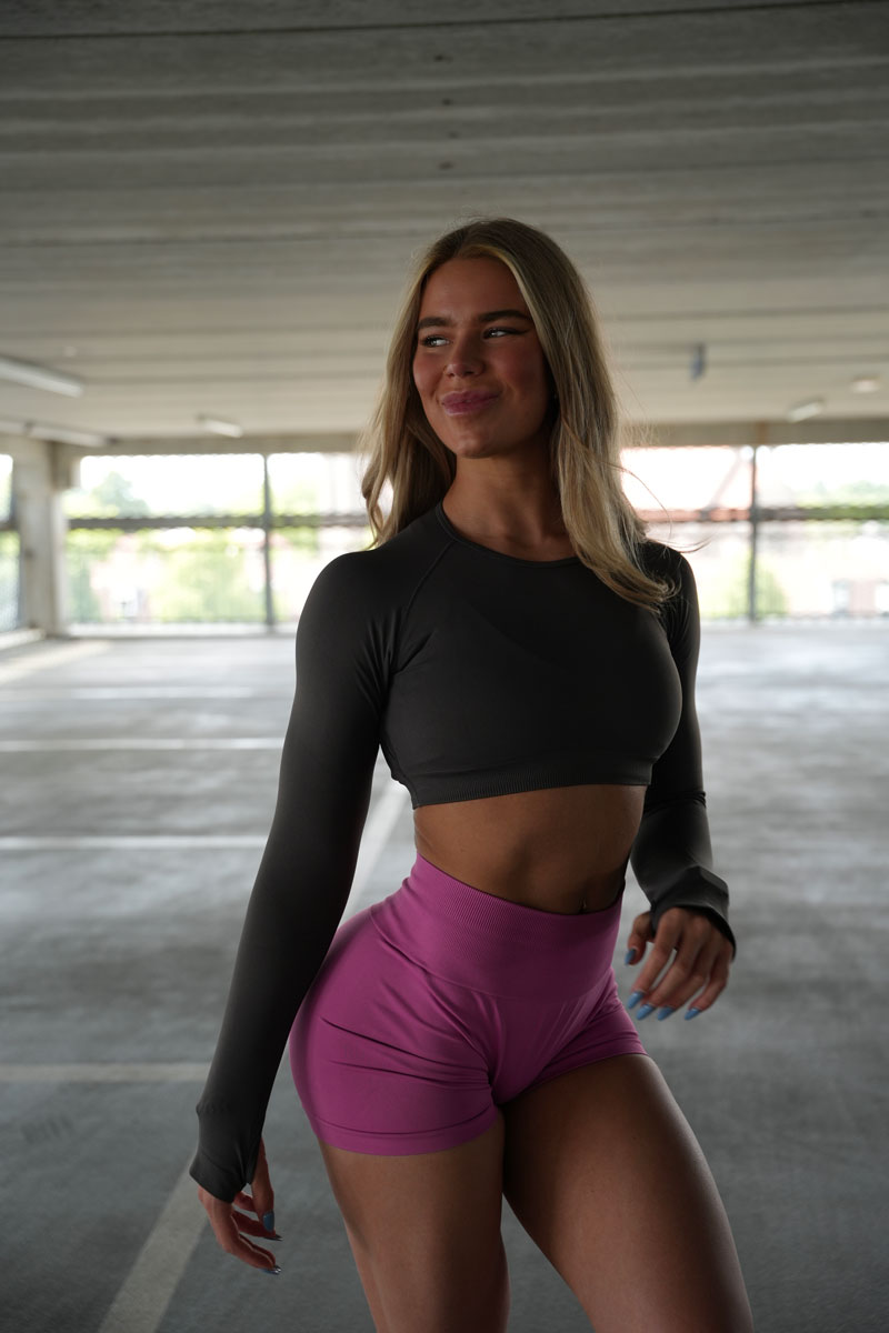 De coach lacht terwijl hij een roze korte broek draagt.